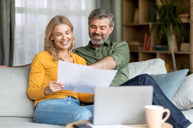 Happy Middle Aged Couple Reading Documents At Home